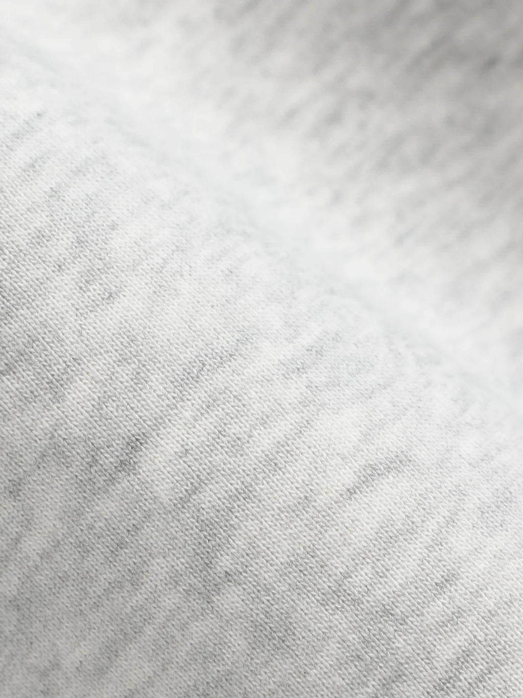 Close-up of the grey melange cotton fabric texture on a CASPARA sweatshirt.